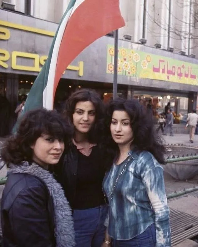 ইরানের পতাকার সামনে জিন্স, টিশার্ট স্কার্ফে তরুণীরা