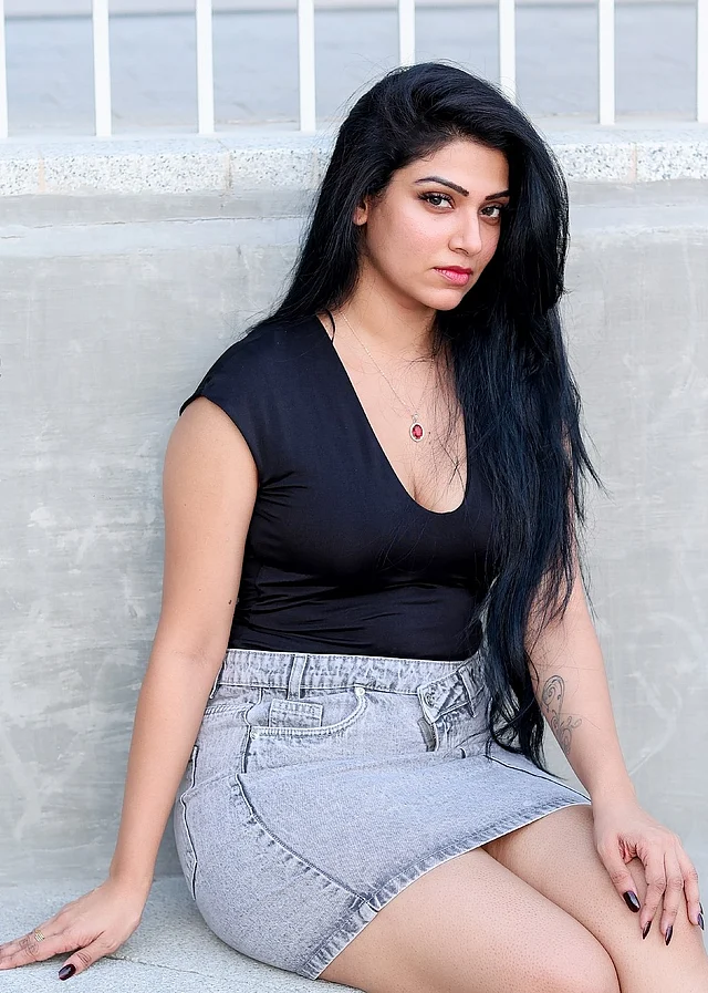 কালো ডিপনেক টপ আর হাই ওয়েস্টেড ডেনিম মিনিস্কার্টে দেখা যাচ্ছে তাঁকে