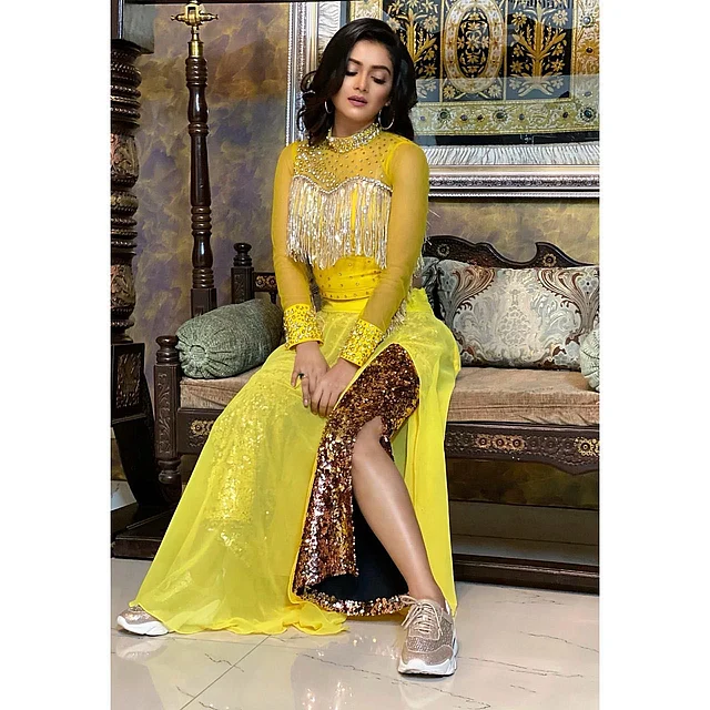 হলুদ থাই স্লিট ড্রেসের সঙ্গে নজর কাড়ছে সোনালি স্নিকার্স