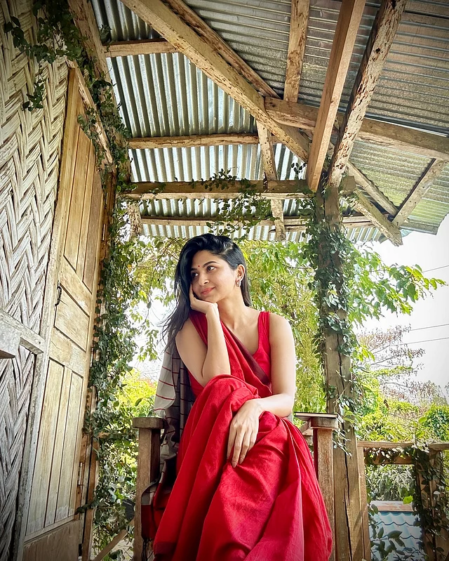 এখানে তিনি পরেছেন ম্যাচিং স্লিভলেস ব্লাউজের সঙ্গে লাল তাঁতের শাড়ি