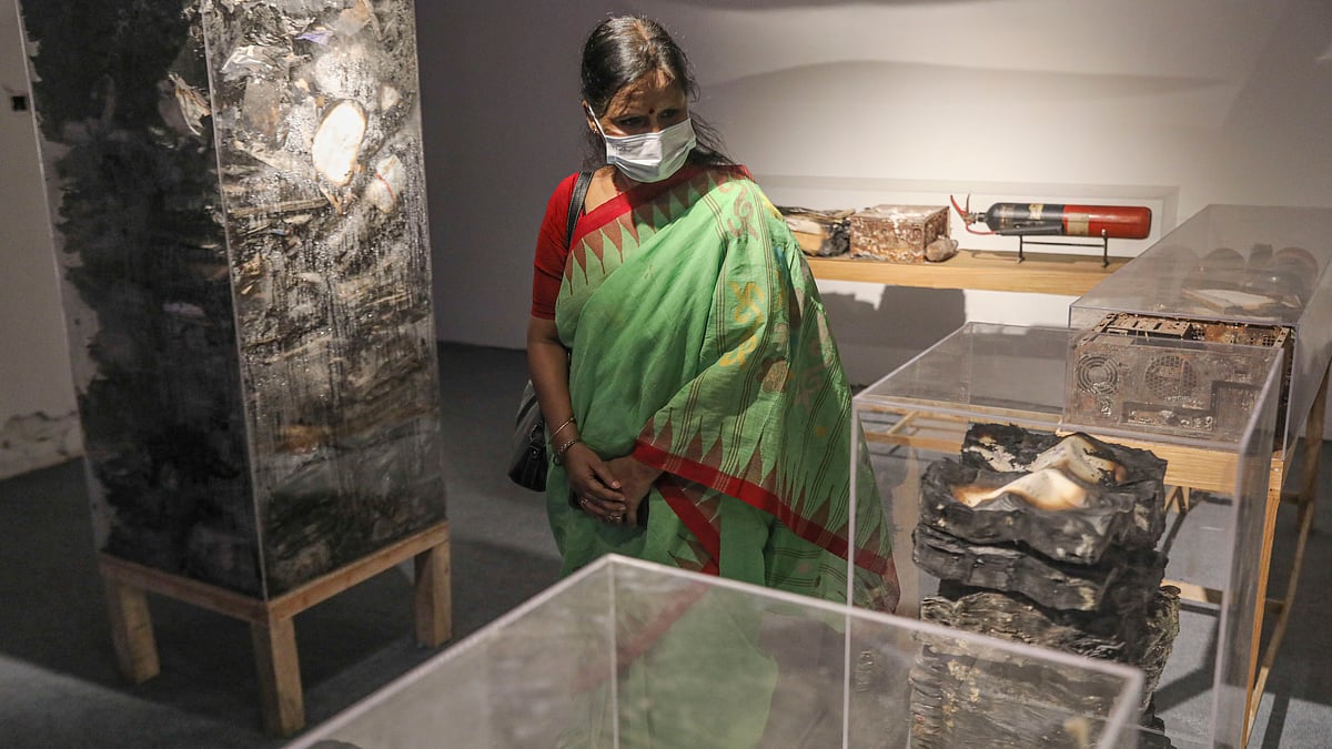 পুড়ে যাওয়া পত্রিকা ও মূল্যবান মালামাল কাচের বাক্সে রাখা, তা দেখছেন এক দর্শনার্থী