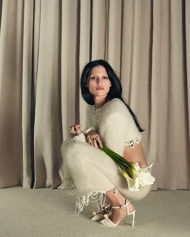 মুক্তার লেয়ার দেওয়া আইভরি উলের ফিউশন টু-পিস ড্রেসের সঙ্গে পরেছেন মুক্তার হাই হিল এবং মাথায় নেটের ভেইল।