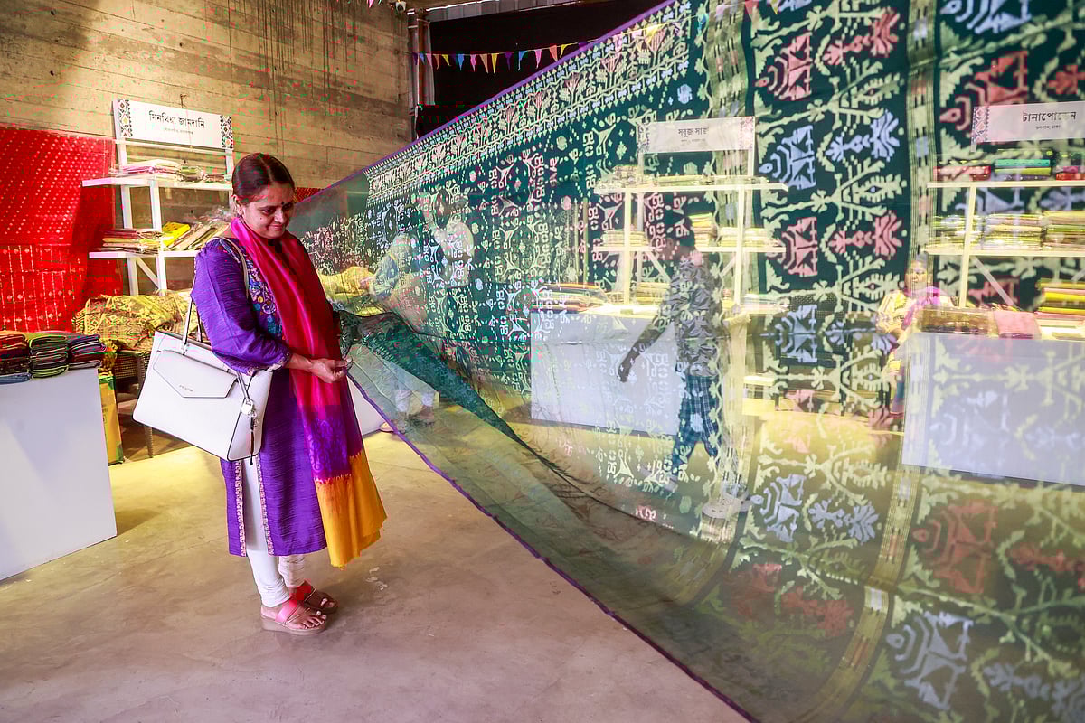 মেলায় জামদানি শাড়ি দেখছেন এক নারী। 