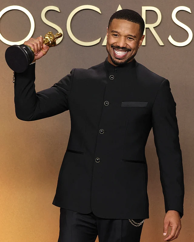 হাই কলার কালো লুই ভিতোঁ জ্যাকেট আর স্ট্রেট কাটের প্যান্টের সঙ্গে সেরা অভিনেতা মাইকেল বি জর্ডান নজর কেড়েছেন ডবল চেইন এমবেলিশমেন্টে