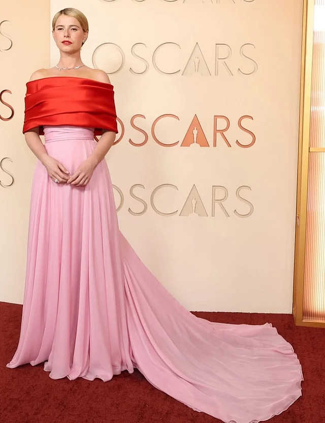 সেরা অভিনেত্রী জেসি বাকলি পরেছেন শ্যানেলের ফ্লোড় টাচ বাবলগাম পিংক গাউন। স্ট্র্যাপলেস গাউনে র‍্যাপ নেকলাইন ডিজাইনে কন্ট্রাস্ট লাল রঙ। 