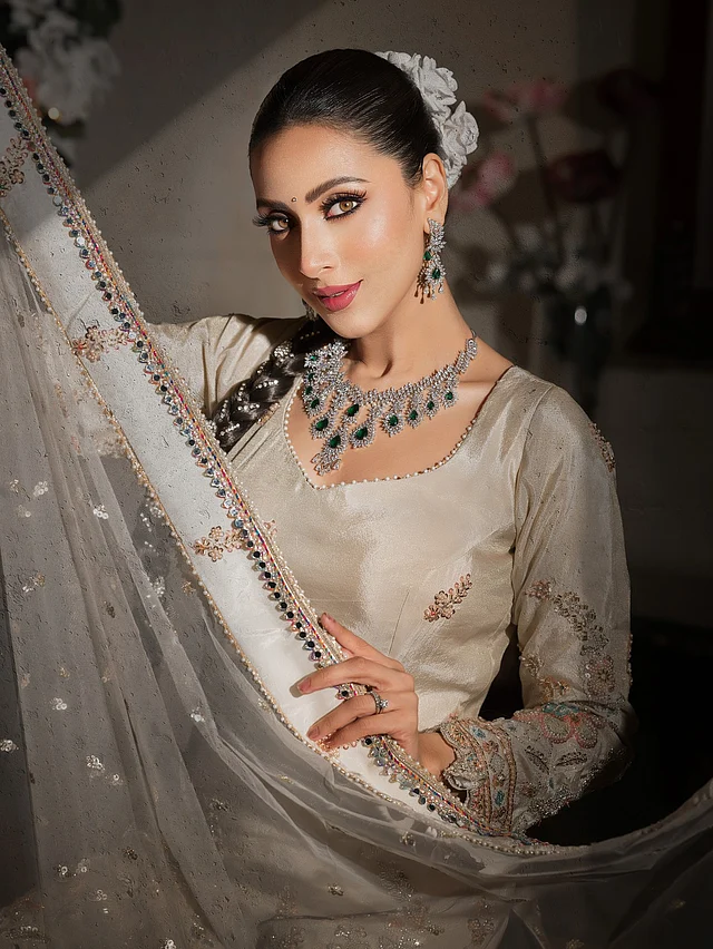 একটু জমকালো আমেজ চাইলে মিমের এই সাজ হতে পারে নিখুঁত অনুপ্রেরণা। হেভি এমব্রয়ডারি করা ক্রিম রঙের সালোয়ার-কামিজের সঙ্গে তিনি পরেছেন ডায়মন্ড-পান্নার গর্জিয়াস সেট। 
তবে আসল আকর্ষণ তার হেয়ারস্টাইল—লম্বা বেণি করে মাথায় সাজানো সাদা ফুল পুরো লুকে আরও জমকালো করেছে। মেকআপেও আছে উৎসবমুখর, রাজকীয় ছোঁয়া।