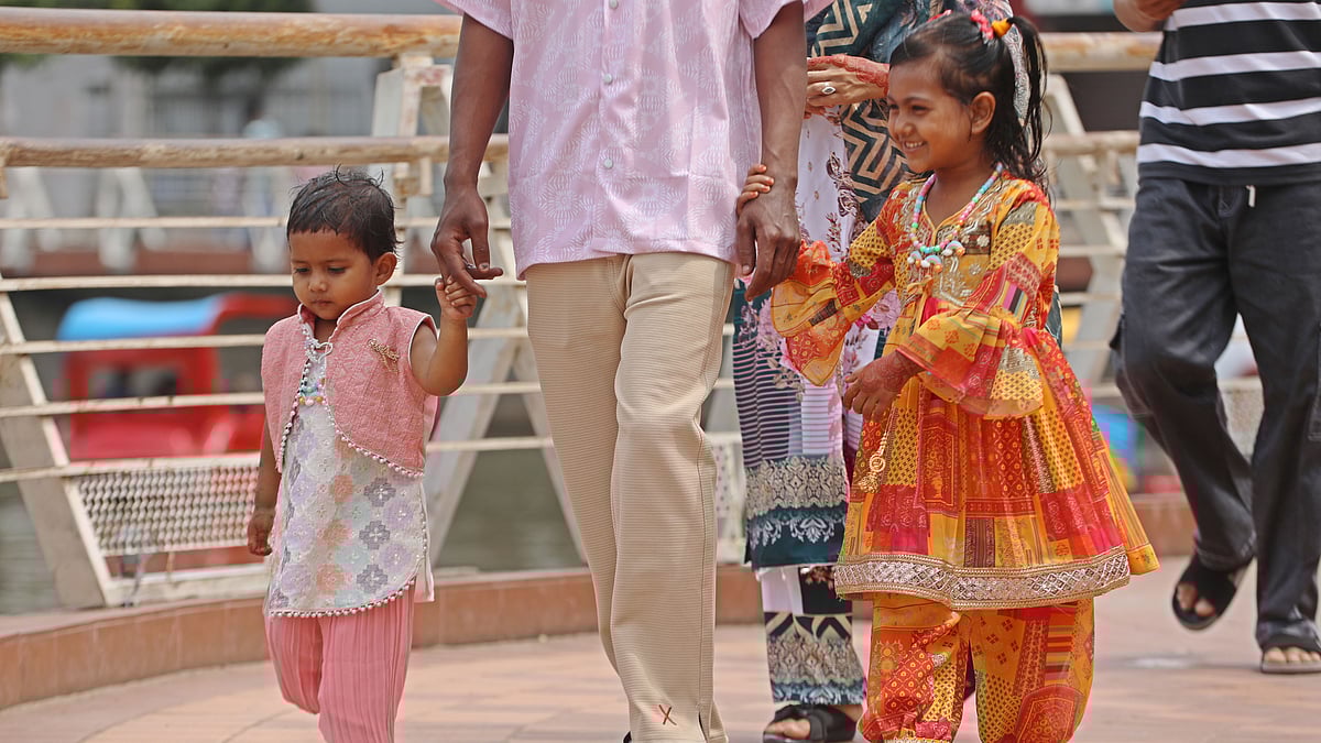 বাবার হাত ধরে ঈদ–আনন্দ উপভোগে দুই শিশু 