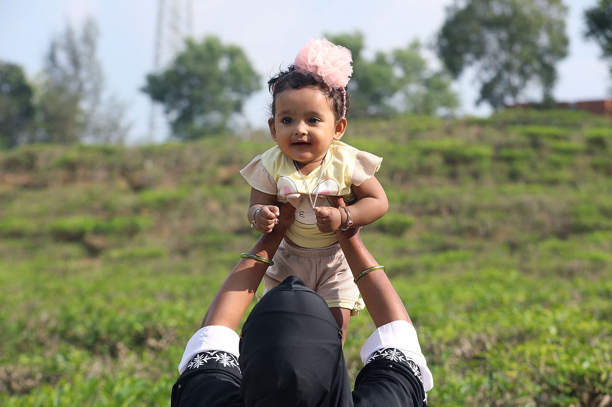 শিশুকে চা–বাগান দেখাতে নিয়ে এসেছেন অভিভাবক।