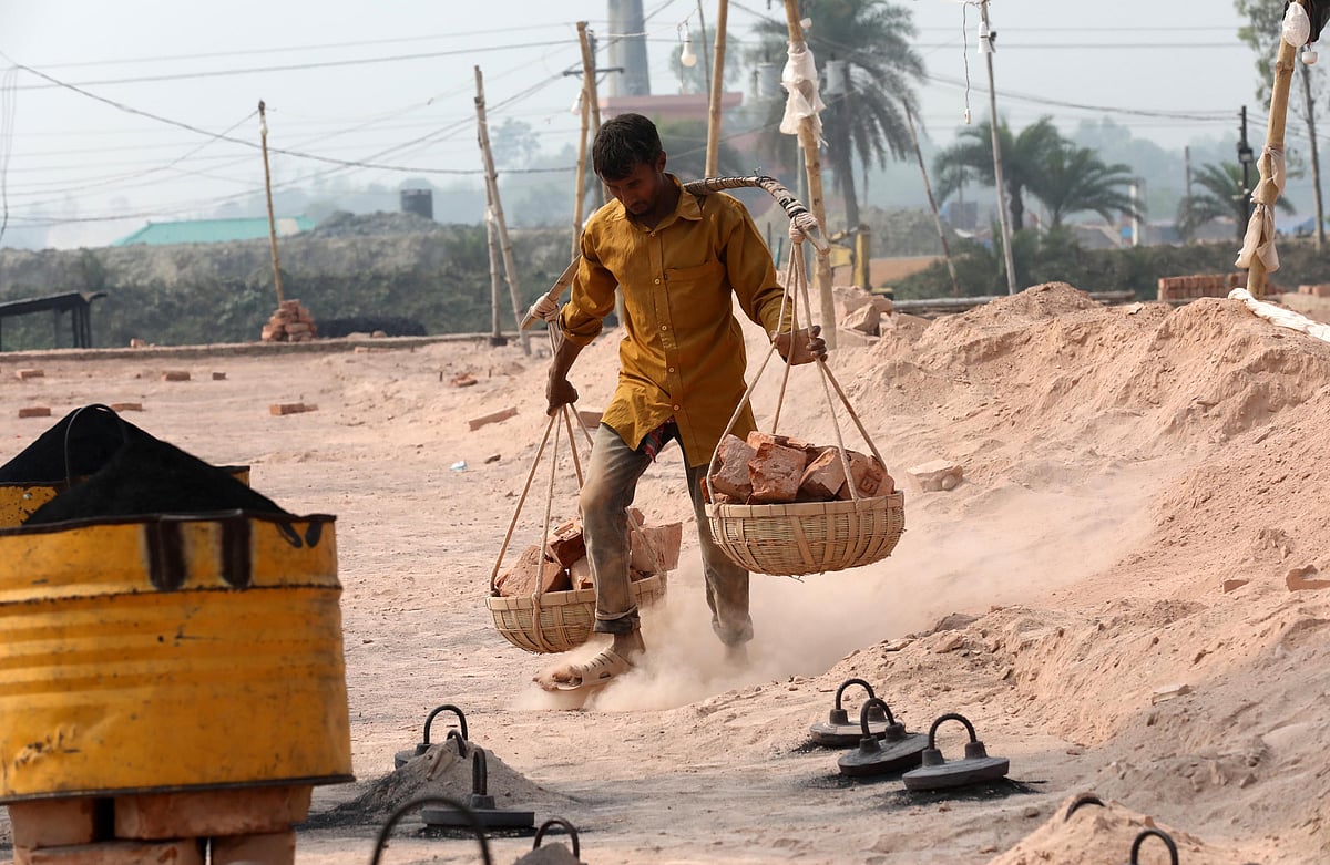 সকালে আলো ফুটেছে। ধুলাবালুর মধ্যে কাজে নেমে পড়েছেন ইটভাটার এক শ্রমিক।
