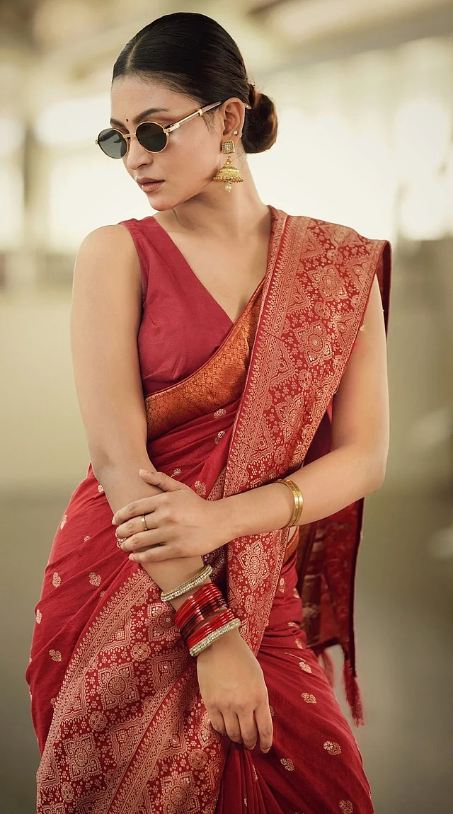 মেরুন চওড়া পাড়ের বেনারসির সঙ্গী হয়েছে স্লিভলেস ব্লাউজ, পরিপাটি খোঁপা, ঝুমকা, চুড়ি আর কালো শেডস