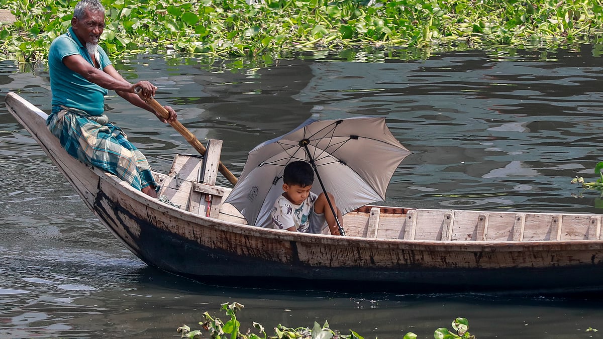 রোদ থেকে বাঁচতে নৌকায় ছাতা মাথায় এক শিশু