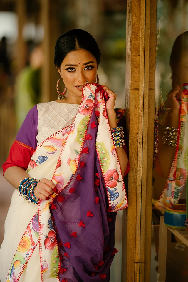 এর বেগুনি আঁচলে অলংকরণ করা হয়েছে লাল ট্যাসেল দিয়ে। 