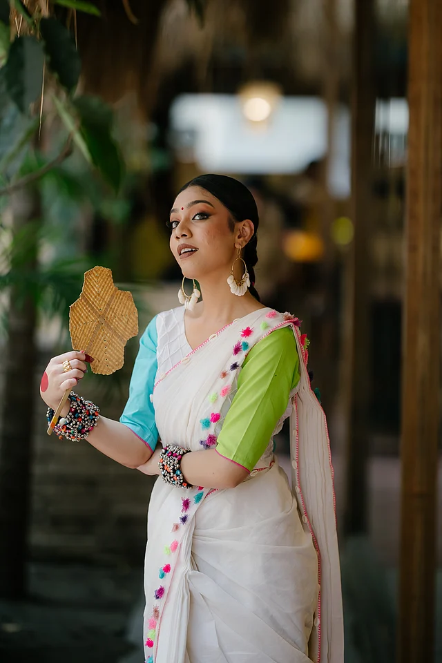 নানা রঙের ট্যাসেল নজর কাড়ছে এই শাড়ির নিচের অংশে। আর ওপরে শোভা পাচ্ছে কড়ি। পাড়ের নকশায় ছোঁয়া আছে হাতের কাজেরও। 