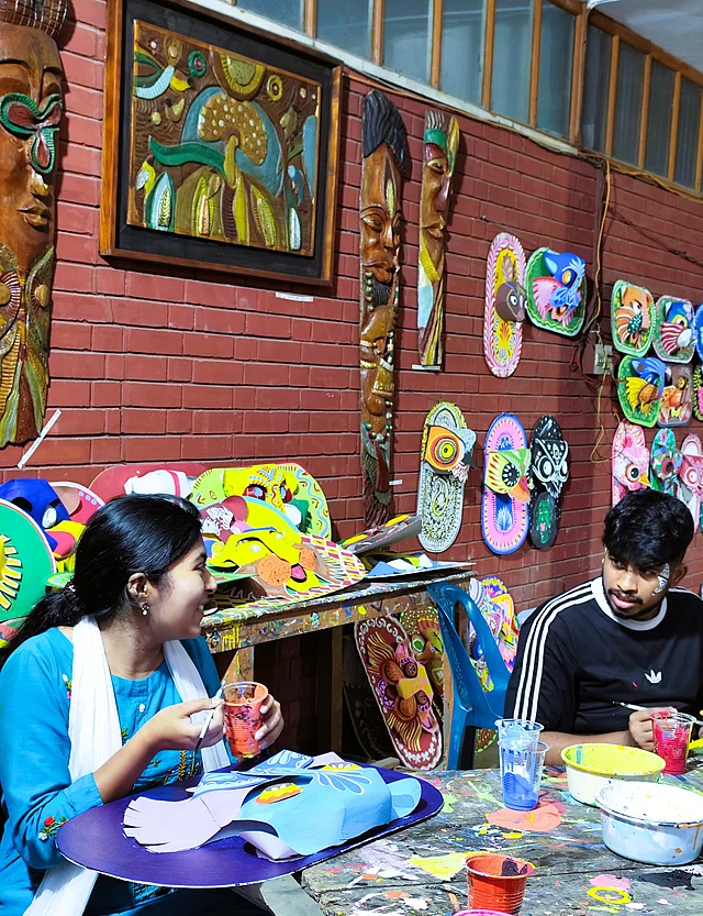 তুলির নিপুণ ছোঁয়ায় ধীরে ধীরে প্রাণ পাচ্ছে বর্ণিল মুখোশ ও শিল্পকর্ম।