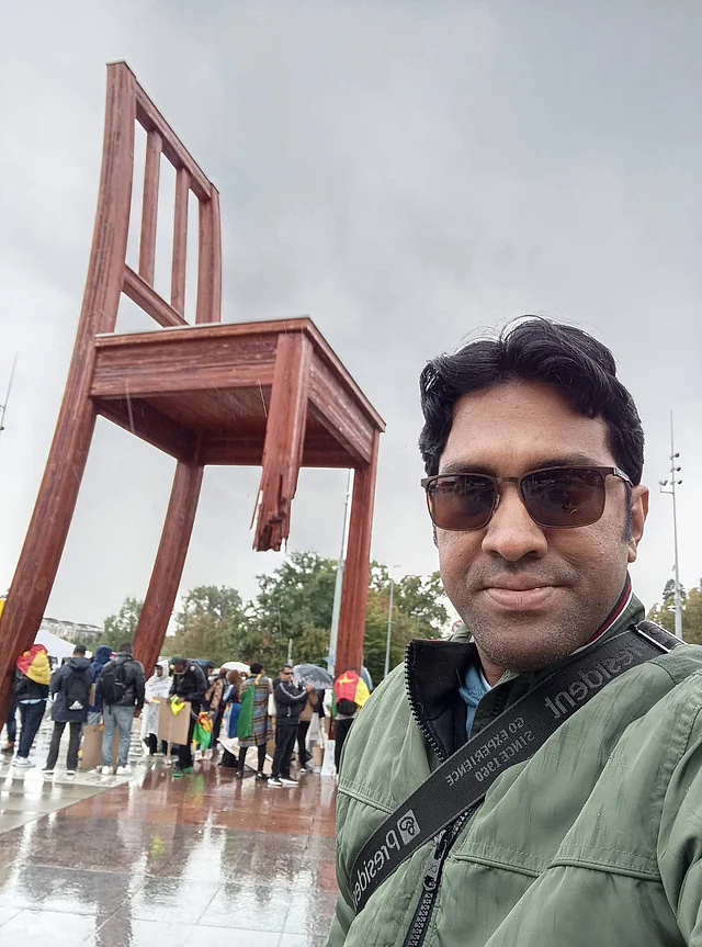 ব্রোকেন চেয়ার এর ভাস্কর্য এর সামনে লেখক