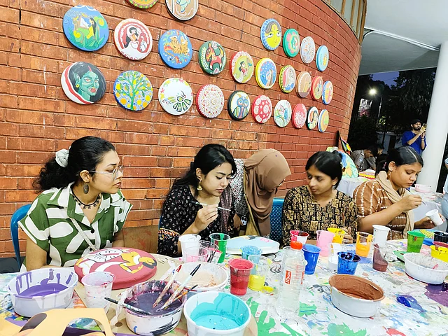 জয়নুল গ্যালারির সামনে মাটির সরায় আলপনা আঁকা আর মুখোশ তৈরির কাজ চলছে পুরোদমে 