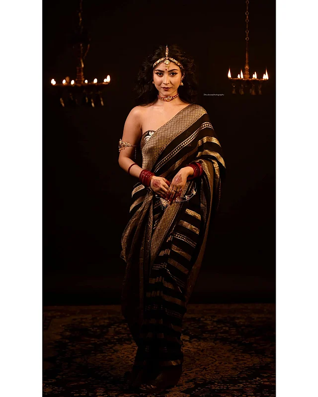 ফিউশন লুকে তিনি পরেছেন স্ট্রেপলেস ব্লাউজ আর সোনালি-কালো স্ট্রাইপের শাড়ি। লাল চুড়ি, মেহেদী তাঁর হাতে। বাহুতে বাজু, কোমরে বিছা, গলায় চোকার আর মাথায় পরেছেন টায়রা। 