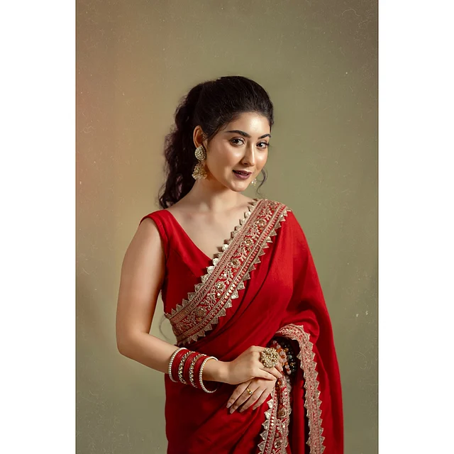 সোনালি পাড়ের লাল শাড়ির সঙ্গে জুটি হয়েছে স্লিভলেস ব্লাউজ। কানে শোভা পাচ্ছে সোনালি ঝুমকা আর এক হাত ভর্তি ম্যাচিং চুড়ি , আংটি । 