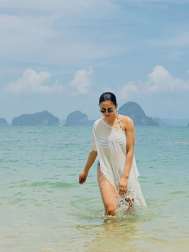 সাদা-নীল স্ট্রাইপ বিকিনির ওপর সাদা সুইম স্যুট কভার-আপ টিউনিক পরেছেন অভিনেত্রী । 