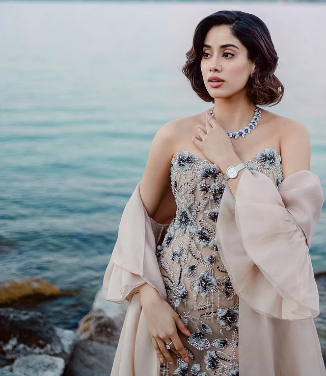 ডিটাচড বেল স্লিভস দেখা যাচ্ছে। ওল্ড হলিউড হেয়ারস্টাইল আর স্টেটমেন্ট নেকলেসের সঙ্গে বম অ্যান্ড মার্সিয়ের ঘড়ি