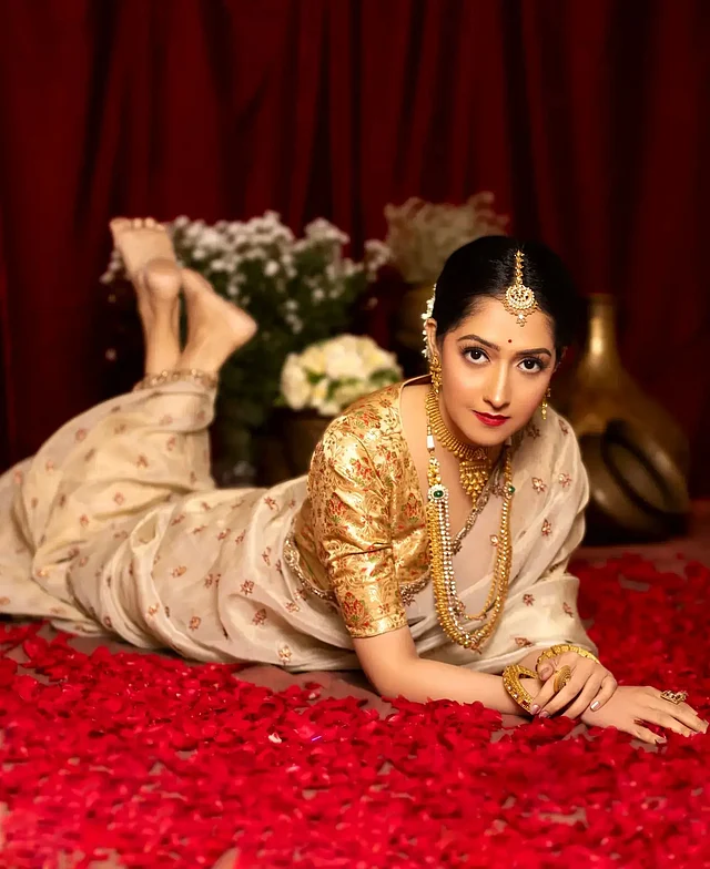 অমৃতা ধরা দিয়েছেন একেবারে ঐতিহ্যবাহী সাজে। ক্রিম ও সোনালি রঙের শাড়ির সঙ্গে গোল্ড ব্রোকেড ব্লাউজ আর  গয়নায় তাঁর লুকে ফুটে উঠেছে রাজকীয় আভা। 