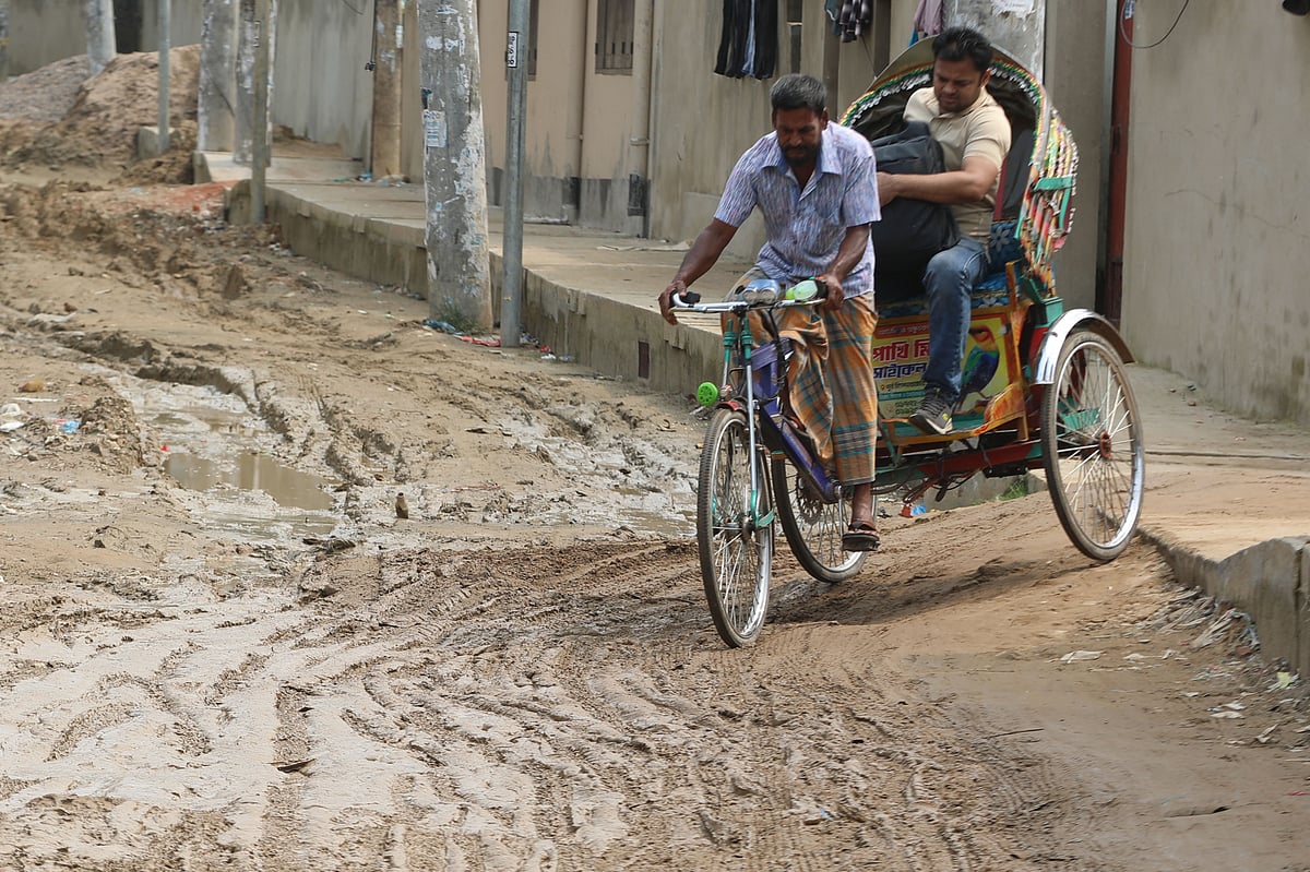 ধীরগতি চলছে সংস্কারের কাজ। সড়কে জমেছে কাদা। পাশ দিয়ে ঝুঁকি নিয়ে চলেছে রিকশা 