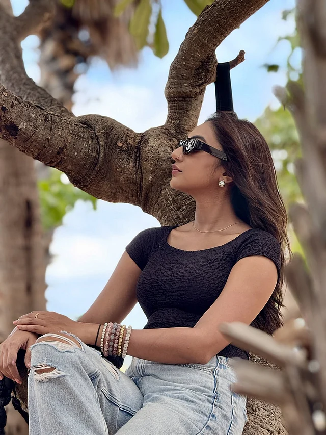 গাহের ডালে বসে সুনেরাহ কালো টপ আর জিন্সের সঙ্গে কালো শেডসে