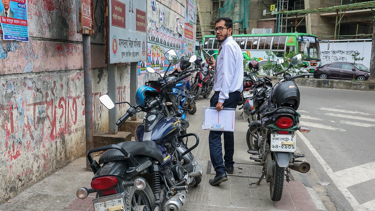 ফুটপাতে রাখা সারি সারি মোটরসাইকেল। মাঝের সংকীর্ণ জায়গা দিয়ে চলছেন পথচারীরা।
