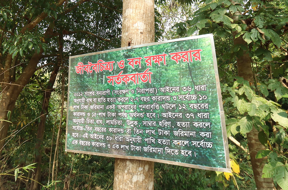 বন ও বন্য প্রাণী রক্ষায় গ্রামবাসীর কঠোর অবস্থানের প্রমাণ; গাছে ঝোলানো সাইনবোর্ডে আইন ও শাস্তির বিধান লিখে সবাইকে সতর্ক করা হয়েছে। 