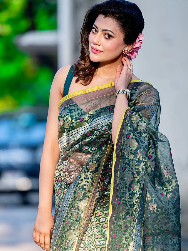 সোনালি-রূপালি ও ম্যাজেন্টার নকশায় বটল গ্রিন শাড়ি পরেছেন তানজিকা । দেখা যাচ্ছে সরু  হলুদ বর্ডার . 