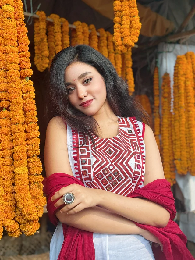 মিররওয়ার্ক ও লাল এমব্রয়ডারি করা সাদা স্লিভলেস কামিজ আর লাল ওড়নায় দেখা যাচ্ছে তাঁকে 
