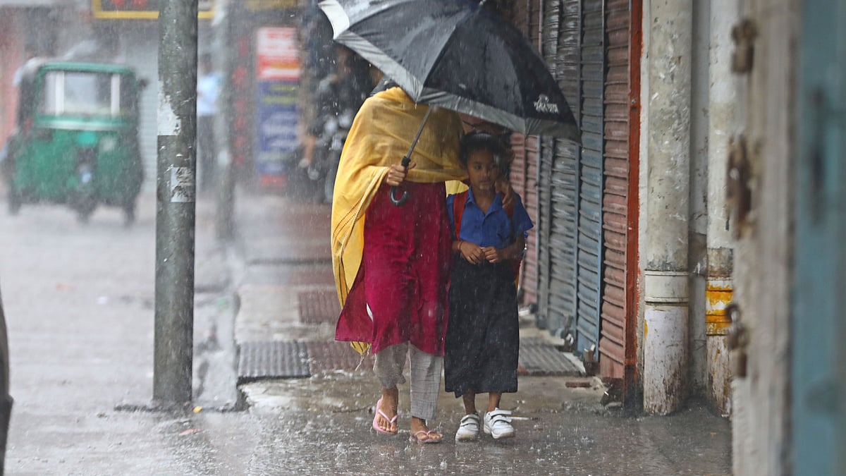 সকালের বৃষ্টির মধ্যে ছাতা মাথায় দিয়ে শিশুকে বিদ্যালয়ে পৌঁছে দিচ্ছেন অভিভাবক
 