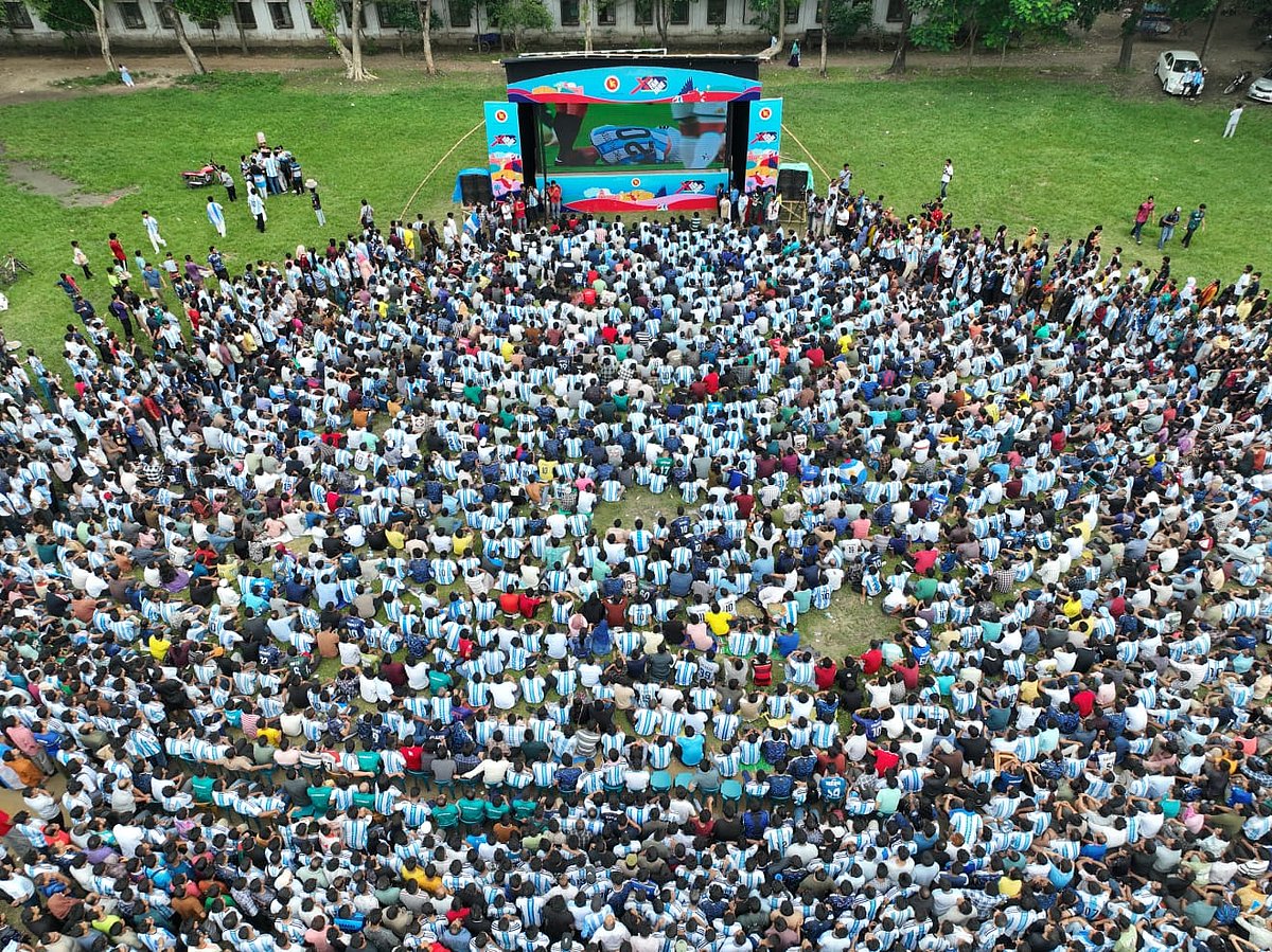 খোলা মাঠে খেলা দেখছেন ফুটবলপ্রেমীরা।