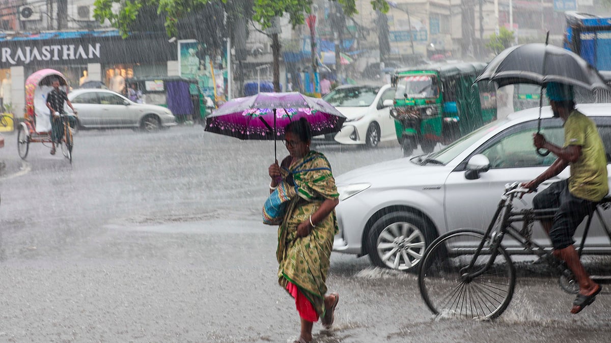 বৃষ্টিতে ছাতা মাথায় নিয়ে গন্তব্যে যাচ্ছেন তিনি।
