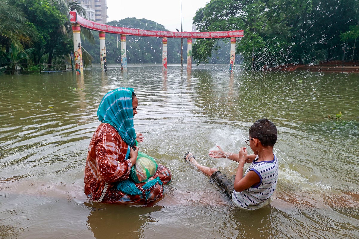 টানা বর্ষণে তলিয়ে যাওয়া ধানমন্ডি লেকের রবীন্দ্রসরোবরে বসে বৃষ্টিভেজার আনন্দে এক নারী ও এক শিশু