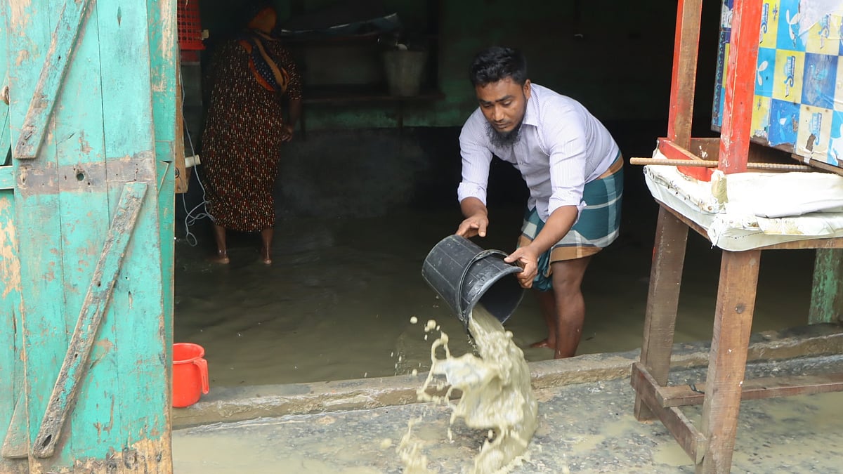 দোকানের ভেতরে জমে থাকা কাদাপানি পরিষ্কার করছেন তিনি