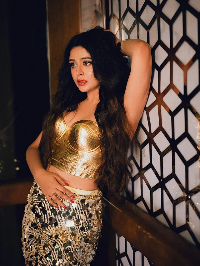 মেকআপে স্মোকি আইজ, হাইলাইটেড চিকবোন আর কোরাল-রেড লিপ শেড, যা পুরো লুকে দিয়েছে গ্ল্যামারাস ও বোল্ড ফিনিশ।