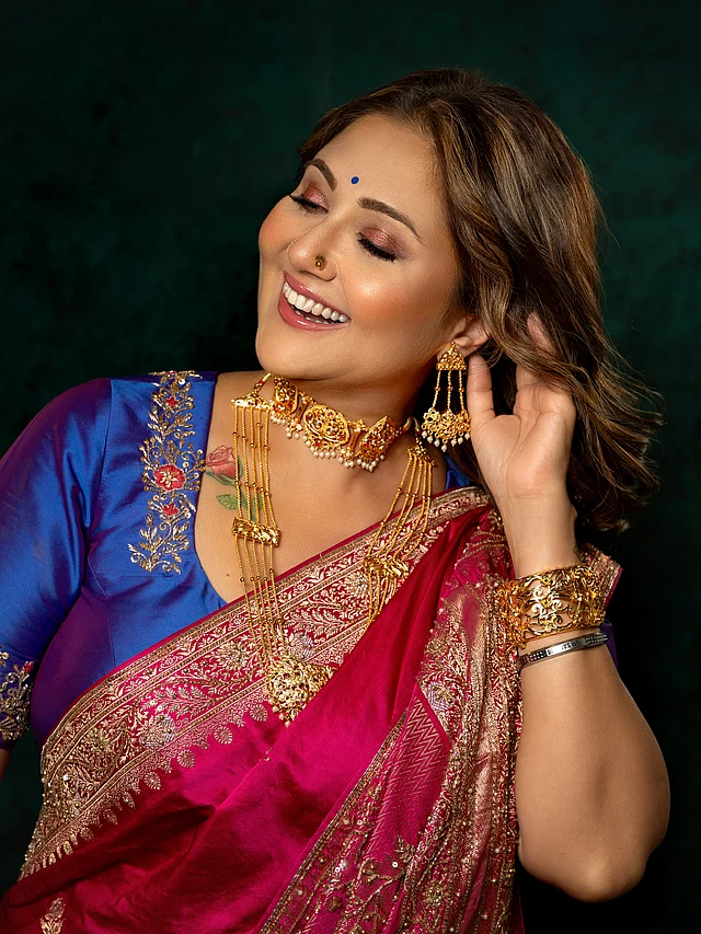গলায় চমৎকার সোনার সীতাহার, চোকার ও ম্যাচিং গয়না; আর সেজেছেন কপালে নীল টিপ ও ঐতিহ্যবাহী সাজে।
