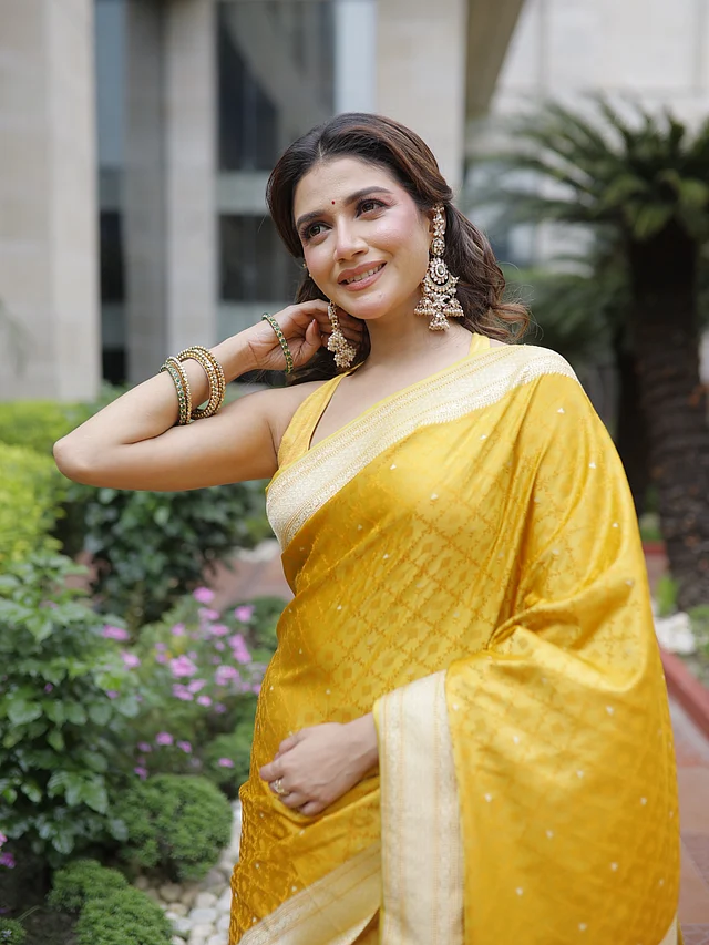সৌরসেনী মৈত্রকে দেখা গেছে জমকালো বাসন্তী হলুদ বেনারসি সিল্ক শাড়িতে। সঙ্গে ম্যাচিং হল্টার নেকের স্লিভলেস ব্লাউজ পরেছেন। কানে বড় কুন্দনের ঝুমকা, হাতে চুড়ি আর গোলাপি আভার মেকআপে অভিনেত্রীর সাজে ফুটে উঠেছে স্নিগ্ধতা ও উৎসবের আমেজ।
