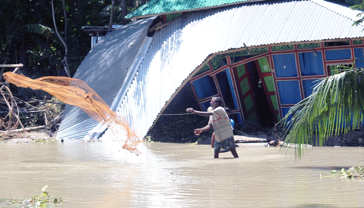 বাড়ির উঠানে মাছ ধরছেন এক গৃহস্থ। জোয়ার-জলোচ্ছ্বাসে ভোলা সদর উপজেলার পূর্ব ইলিশা ইউনিয়নের ছয়টি গ্রামের মানুষ এখন পানিবন্দী। গতকাল দুপুরে উপজেলার সাজিকান্দি এলাকায়।