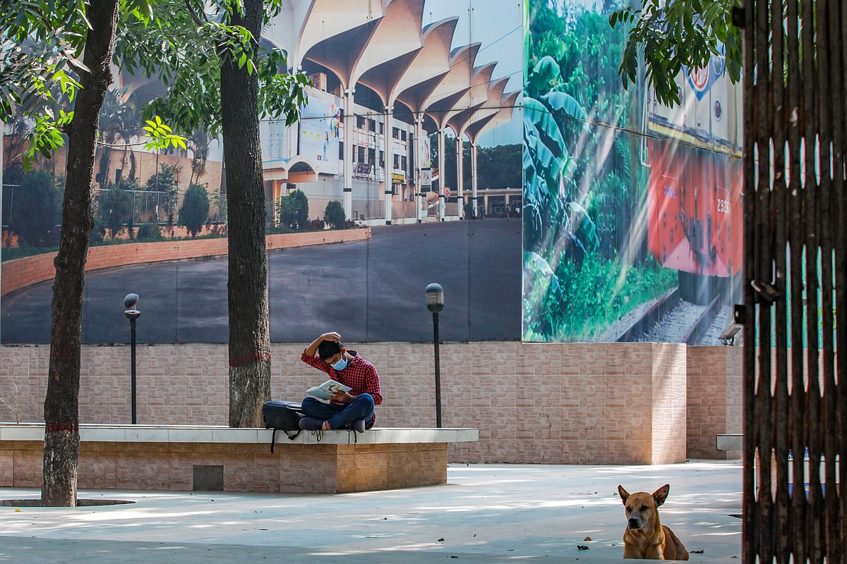 ট্রেনের অপেক্ষায় গাছের ছায়ায় বসে বই পড়ছেন এক যাত্রী। এমন পাঠকদের জন্য রেলস্টেশনেও ছোট গ্রন্থাগার গড়ে তোলা হবে