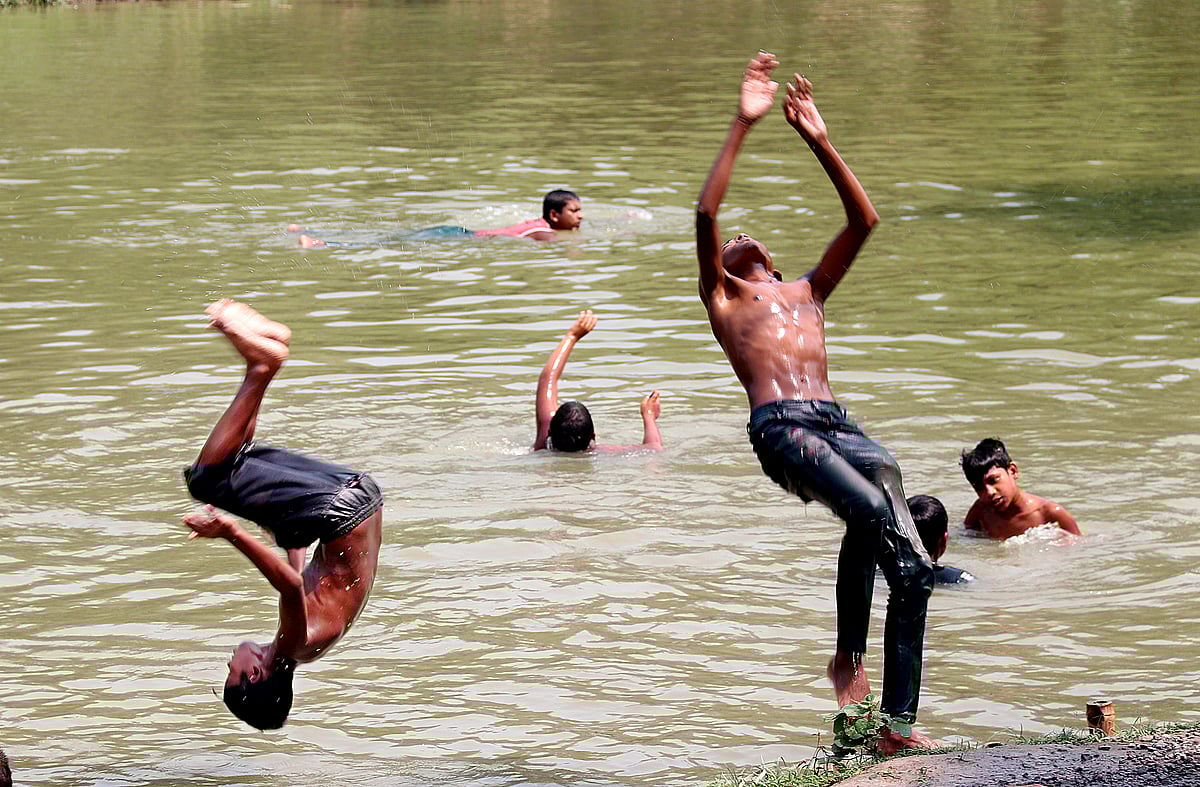 গরমে প্রাণ জুড়াতে একদল শিশু-কিশোর দুরন্তপনায় মেতে উঠেছে। নাজিরশংকরপুর, যশোর, ২৯ এপ্রিল