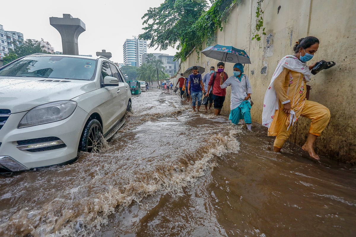 বৃষ্টির কারণে সড়কে সৃষ্ট জলাবদ্ধতায় ভোগান্তিতে পথচারীরা। শাহবাগ এলাকা, ঢাকা, ২১ জুন।
