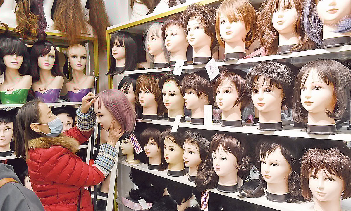 চীনের একটি পরচুলার দোকানে চুল সাজিয়ে রাখছেন এক বিক্রয়কর্মী