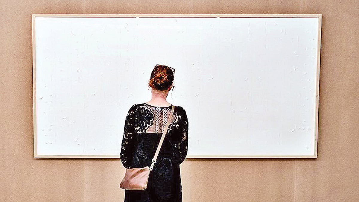 সাদা ক্যানভাসের সামনে একজন দর্শনার্থী