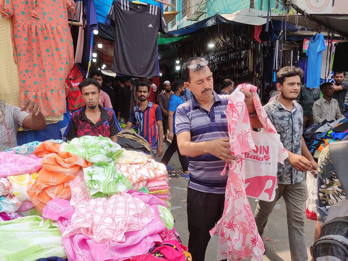 গুলিস্তানে ফুটপাতে সন্তানের জন্য পোশাক পছন্দ করছেন একজন