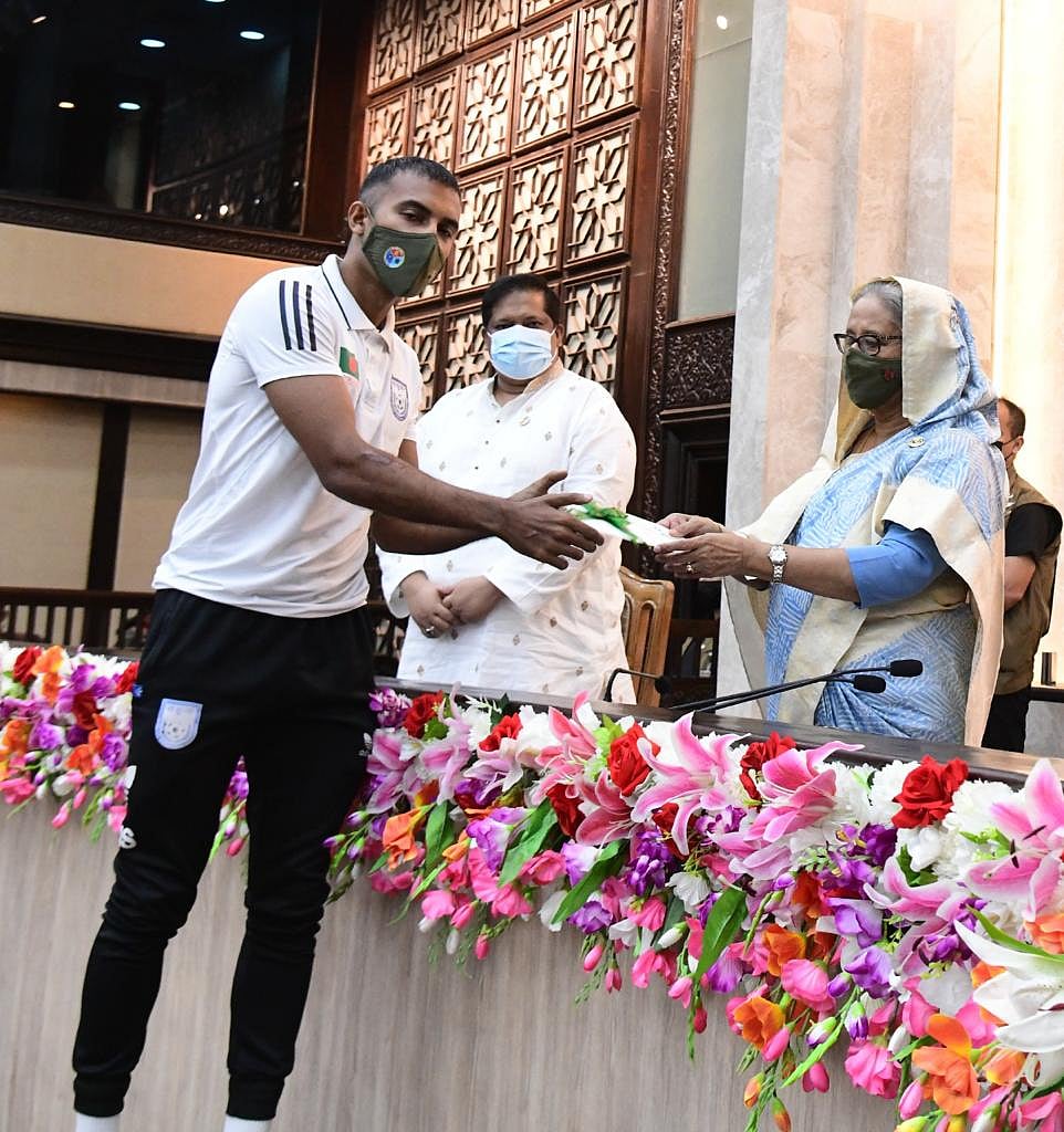 প্রধানমন্ত্রী শেখ হাসিনার কাছ থেকে চেক নিচ্ছেন জাতীয় ফুটবল দলের অধিনায়ক জামাল ভূঁইয়া