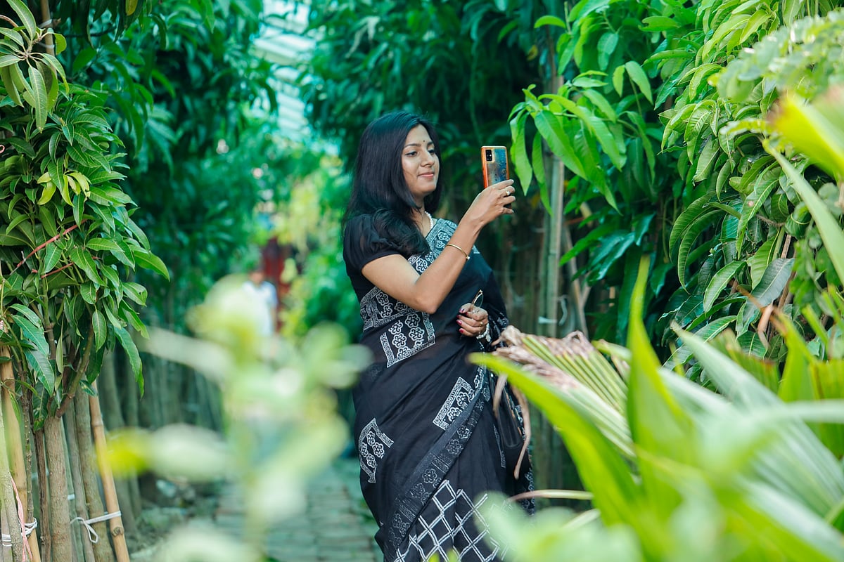 গাছের ছবি তুলছেন মেলায় আসা এক দর্শনার্থী