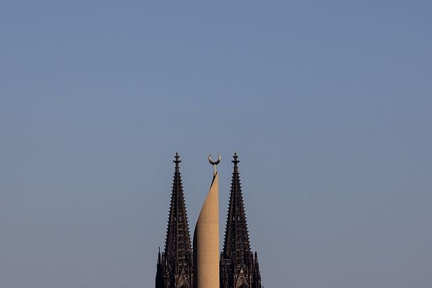 কোলনের কেন্দ্রীয় মসজিদের মিনারের পেছনে বিখ্যাত জোড়া ক্যাথেড্রালের মিনার