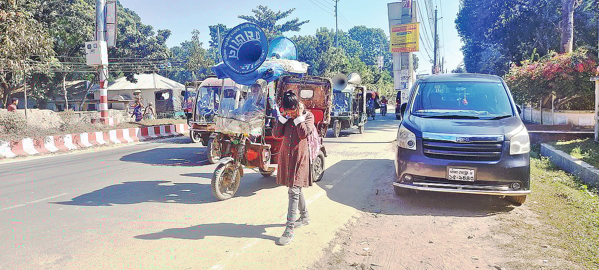 ঠাকুরগাঁও শহরের বঙ্গবন্ধু সড়কে ইজিবাইকে মাইকিং করা হচ্ছে। সে শব্দ থেকে রক্ষায় নিজের দুই কান চেপে ধরেছে এক শিশু। সাম্প্রতিক ছবি